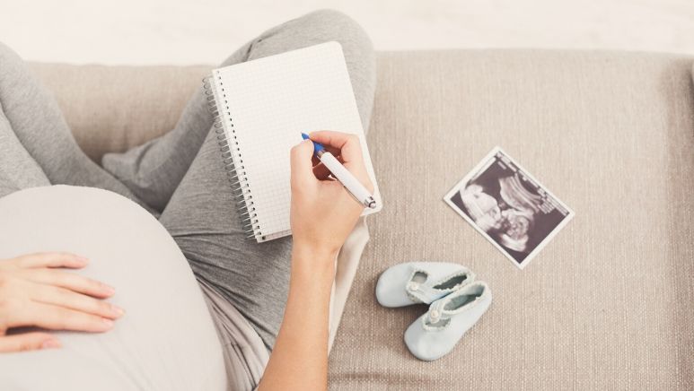 femme enceinte prenant des notes sur son canapé