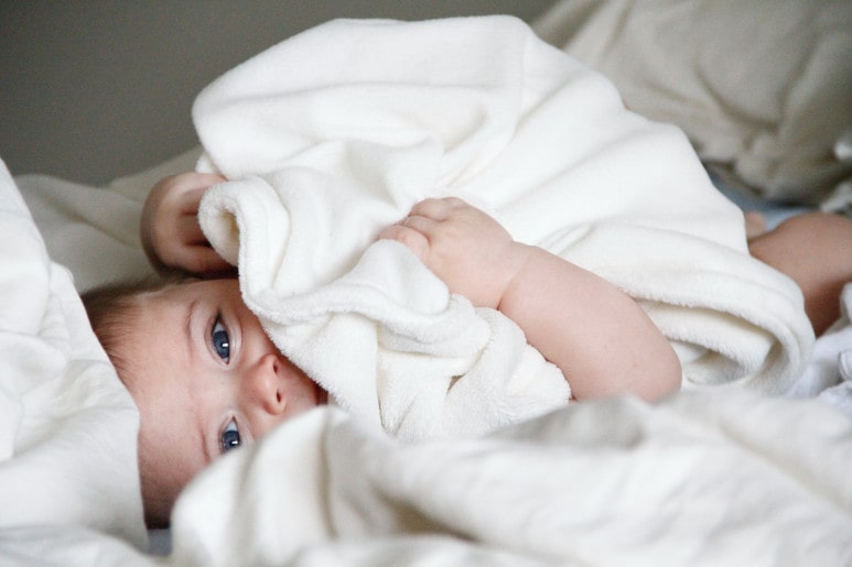 bébé emmitouflé dans une serviette blanche après son retour à la maison