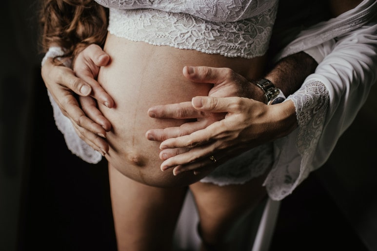 Femme enceinte avec mains du pere pendant une séance d'haptonomie
