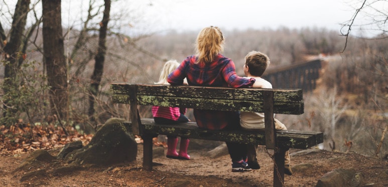 Maman et ses enfants sur un banc dans la forêt
