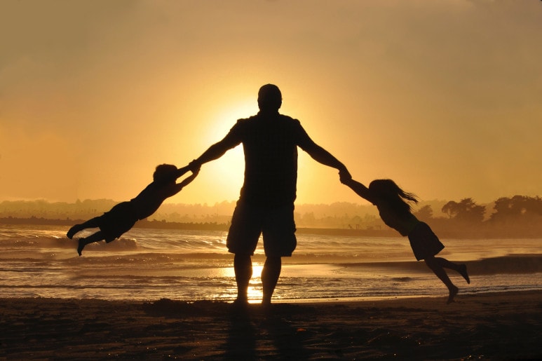 Parent sur la plage avec ses deux enfants
