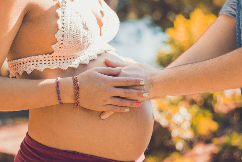 une femme enceinte avec les mains de son conjoint