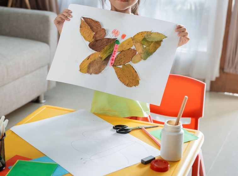 Enfant en train de faire une activité dessin à l'aide de feuille d'arbre